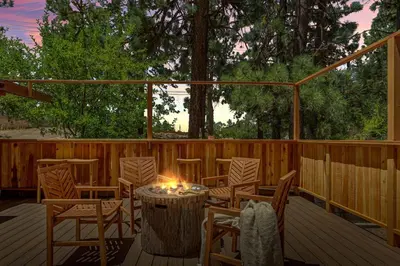 a wooden deck with chairs and a table with a candle at Lawliss Hideout in Big Bear Lake in Big Bear Lake