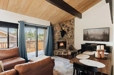 a living room with a table and a fireplace at Solace Cabin in Big Bear Lake