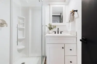 a white bathroom with a shower and a sink at Solace Cabin in Big Bear Lake