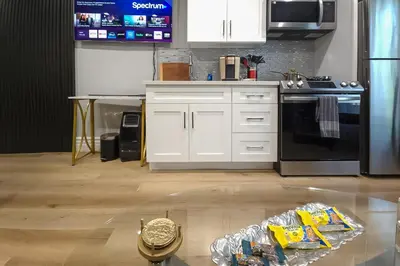 a kitchen with white cabinets and a black refrigerator at Walk to Hollywood Blvd Chic LA Studio with Patio! in Los Angeles