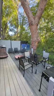 a deck with tables and chairs and a tree at Joyful Place in Sherman Oaks
