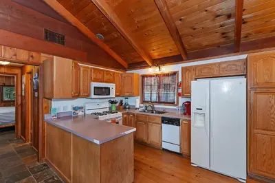 a kitchen with wooden cabinets and a white refrigerator at Emerald Arrowhead Haus - For 6 in Lake Arrowhead