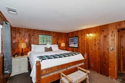 a bedroom with wooden walls and a bed and a chair at Emerald Arrowhead Haus - For 6 in Lake Arrowhead