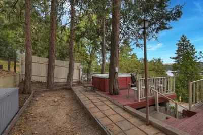 a house with a porch with a bench and trees at Emerald Arrowhead Haus - For 6 in Lake Arrowhead