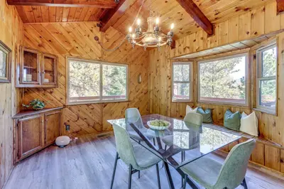 a dining room with a glass table and chairs at Deck and Views Modern Cabin Near Lake Arrowhead! in Lake Arrowhead
