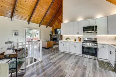 a kitchen with white cabinets and a wooden ceiling at Deck and Views Modern Cabin Near Lake Arrowhead! in Lake Arrowhead