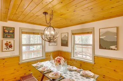 a dining room with a table and two windows at 3 Mi to Snow Summit Charming Home with Fenced Yard in Big Bear Lake