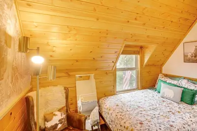 a log cabin bedroom with a bed and a window at 3 Mi to Snow Summit Charming Home with Fenced Yard in Big Bear Lake