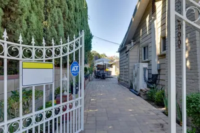 a white fence with a sign on it next to a building at 4 Mi to Old Pasadena Walkable Studio in Alhambra