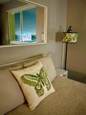 a butterfly pillow on a bed with a window at Stylish Studio in Mid-Wilshire with Pool, Free Parking, Gym in Prime Location in Los Angeles