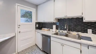 a kitchen with white cabinets and a sink at Cozy Hollywood Hideaway w Private Patio Easy City Access Casa Camrose by AvantStay in Los Angeles
