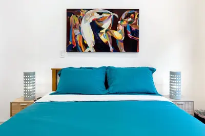 a bedroom with a blue bed and a painting on the wall at Platinum Suite LA in Los Angeles