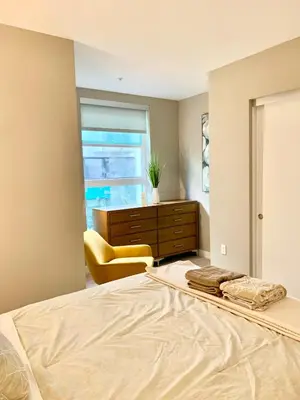 a bedroom with a bed and a chair and a window at Contemporary 2BR Prime Hollywood Location in Los Angeles