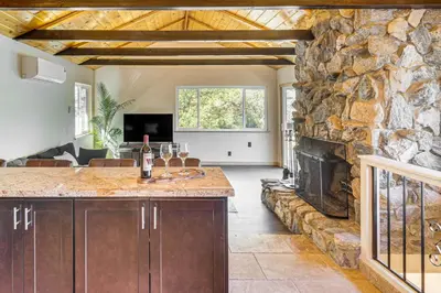 a living room with a stone wall and a fireplace at Walk to Village! Romantic Pine Mtn Nature Escape in Pine Mountain Club