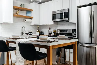 a kitchen with white cabinets and a table with wine glasses at High End Hotel Style 2B apartment with two balconies in Los Angeles