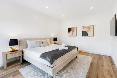 a white bedroom with a large bed and two lamps at Sky Haus LA in Los Angeles