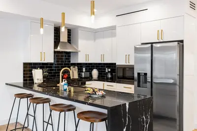 a kitchen with white cabinets and a black counter top at Sky Haus LA in Los Angeles