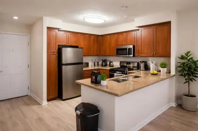 a kitchen with wooden cabinets and a stainless steel refrigerator at Marina Del Rey Apartment with Resort Amenities - Short Distance To Venice Beach in Los Angeles