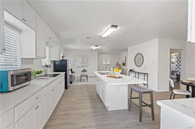 a kitchen with white cabinets and a table and chairs at 4 bedrooms in Long Beach