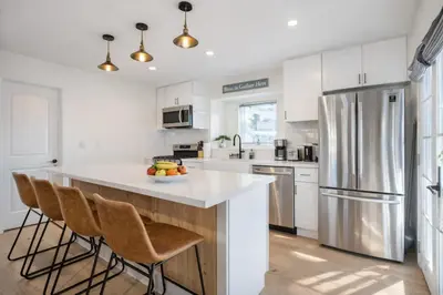 a kitchen with white cabinets and a stainless steel refrigerator at Modern 3BR Home Near USC, Museums & Coliseum in Los Angeles