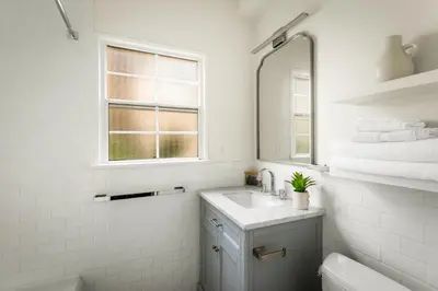 a white bathroom with a sink and a mirror at Beverly Grove Hotel in Los Angeles