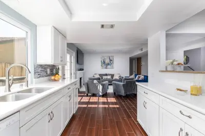 a kitchen with white cabinets and a living room at Heidi House Entire Duplex Relocation Stays in Redlands