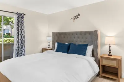 a bedroom with a large bed with blue pillows at Pool Hot Tub King Bed 1st Floor Condo in Corona