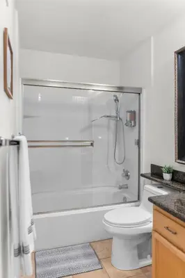 a white bathroom with a shower and a toilet at Pool Hot Tub King Bed 1st Floor Condo in Corona