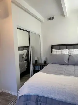 a white bedroom with a bed and a mirror at San Pedro Delight in San Pedro Peninsula Hospital Heliport