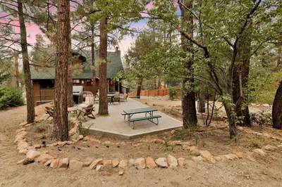 a picnic table in front of a house with trees at Lakeview Pines Log Cabin #2585 in Big Bear Lake