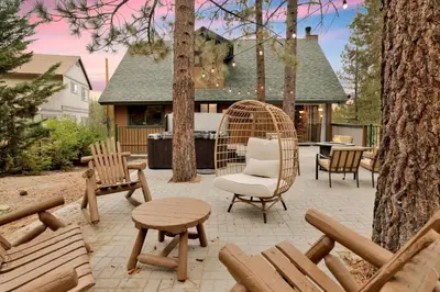 a patio with a wicker chair and a table and benches at Lakeview Pines Log Cabin #2585 in Big Bear Lake
