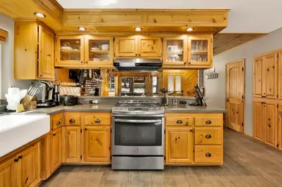 a kitchen with wooden cabinets and a stove top oven at Golden West Cottage #2581 in Big Bear Lake