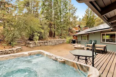 a hot tub on a wooden deck with a table at Arlberg Village Haus #2571 in Big Bear Lake