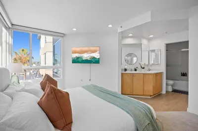 a white bedroom with a large bed and a bathroom at Waterfront Penthouse - Marina Views - Rooftop in Los Angeles