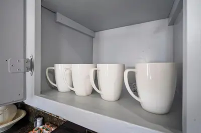 four white cups sitting on a shelf in a kitchen at Darling 2 bedroom 1 bathroom Highland Park Home with Jacuzzi and View in Los Angeles