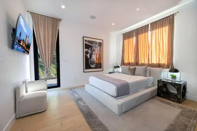 a bedroom with a white bed and a chair at Luxury 6BR Beverly Hills Villa with Pool and Views in Los Angeles