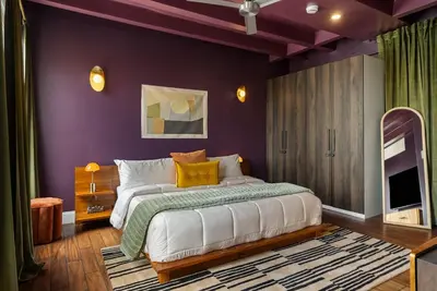 a bedroom with a large bed with purple walls at Ocean-View 1BR Condo in Historic Cooper Arms in Long Beach