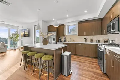 a kitchen with wooden cabinets and a island with bar stools at Sapphire Marina - Marina View Pool, Gym, Game Room in Los Angeles