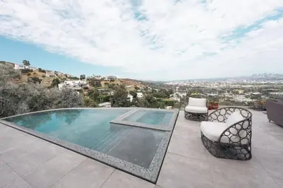 a swimming pool on a patio with two chairs at Serene Glasshouse Retreat with Iconic LA Skyline Views in Los Angeles