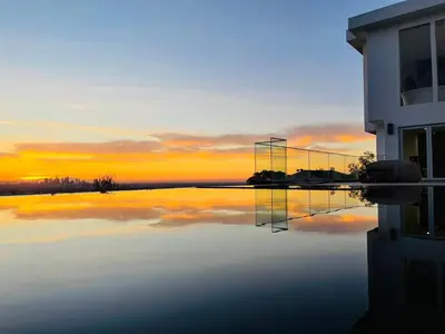 a reflection of a building in the water at sunset at Hollywood Hills Glass Cabin-Skyline view -Floor to Ceiling Windows in Los Angeles