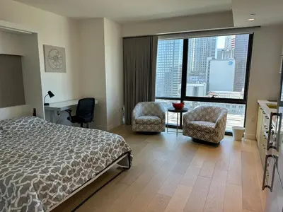 a bedroom with a bed and two chairs and a large window at DTLA Luxury Studio in Los Angeles