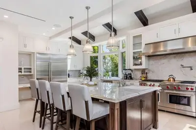 a kitchen with white cabinets and a large island with bar chairs at Summitridge Bev Hills Villa with Pool, Spa, Roof Deck in Beverly Hills