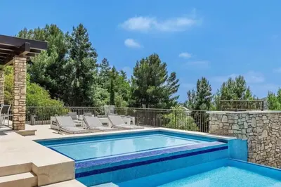 a swimming pool with lounge chairs next to a stone wall at Summitridge Bev Hills Villa with Pool, Spa, Roof Deck in Beverly Hills