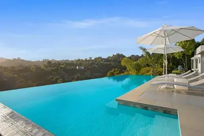 a large swimming pool with an umbrella and chairs at Beverly Hills Mansion W. Stunning Views in Beverly Hills