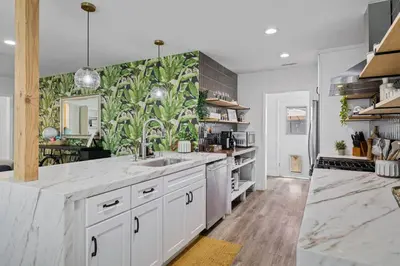 a kitchen with white cabinets and a green wall at Pool House Retreat near LAX, SoFi & Beach in Inglewood