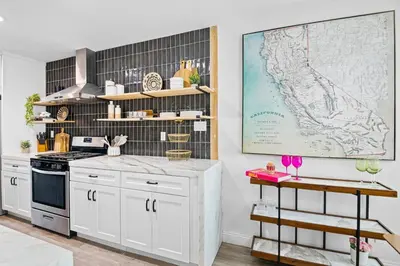 a kitchen with white cabinets and a map on the wall at Pool House Retreat near LAX, SoFi & Beach in Inglewood
