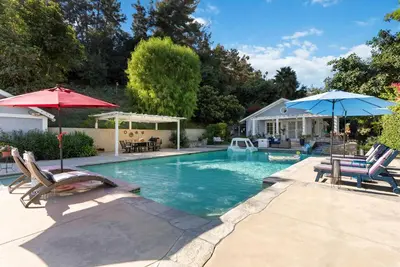 a swimming pool with two chairs and two umbrellas at Luxury LA Garden Estate Private Pool HotTub Tennis in La Habra