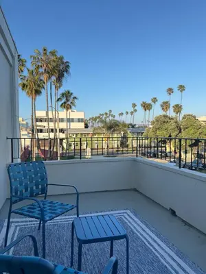 two blue chairs on a balcony with palm trees at Charming Modern apartment in Santa Monica in Los Angeles