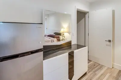 a kitchen with white cabinets and a bed in a bedroom at Work and Play! North Hills Studio 15 Mi to Hollywood in North Hills