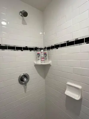 a white tiled bathroom with a toilet and a shelf at Charming Studio Near DTLA AC WiFi Snacks in Los Angeles